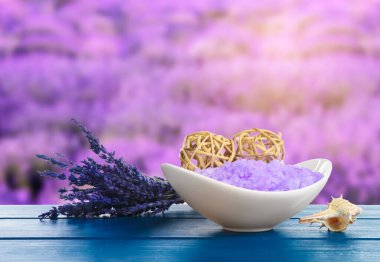 Deniz tuzu kasede ve çiçekler mavi ahşap masada bulanık lavanta tarlasına karşı