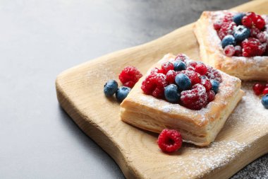 Gri masada böğürtlenli ve pudra şekerli lezzetli puf börekler, yakın plan. Metin için boşluk