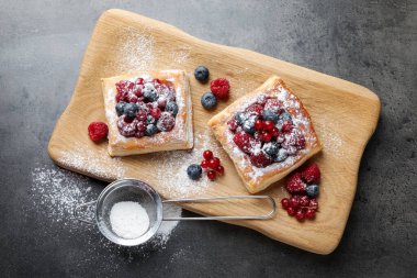 Gri masada böğürtlenli ve pudra şekerli lezzetli puf börekler.