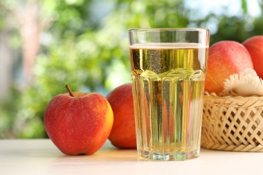 Lezzetli elma şarabı cam ve elmalar beyaz ahşap masa üzerinde, yakın plan