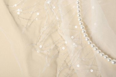 Bej arka planda güzel dantel kumaş ve inciler, üst manzara.