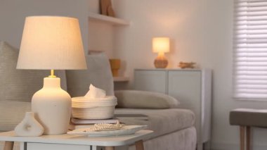 Şık bir lamba, dekorasyon ve beyaz masa üzerine kitap, sola hareket eden kamera.