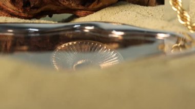 Kum üzerinde güzel altın mücevherlerin şık sunumu, yakın plan. Kamera yukarı hareket ediyor