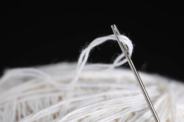 Siyah arkaplanda beyaz iplikli dikiş iğnesi, makro görünüm