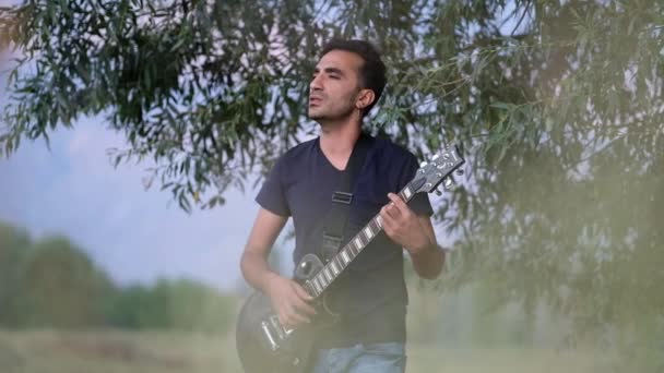 Один Чоловік Грає Гітарі Співає Відкритому Повітрі Тло Ландшафту Кінематографічний — стокове відео