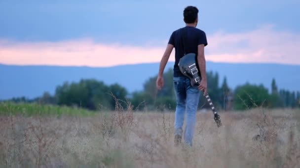 Alkonyatkor Egyedül Sétál Szabadban Gitárral Kezében Táj Gyönyörű Háttere Cinematikus — Stock videók