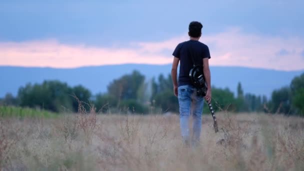 Alkonyatkor Egyedül Sétál Szabadban Gitárral Kezében Táj Gyönyörű Háttere Cinematikus — Stock videók