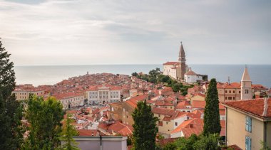Piran, güney Slovenya 'da yer alan güzel eski bir şehirdir. Aziz George Kilisesi manzarası ve eski kasabanın kırmızı kiremitli çatıları. Arka planda Adriyatik Denizini görebilirsiniz.