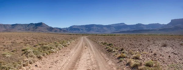 ground road in desert stretching to horizon on blue sky background, Southern African savanna