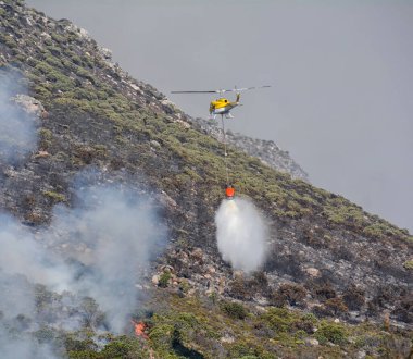 Bir itfaiye helikopteri Güney Afrika 'daki bir yangına su bırakıyor.