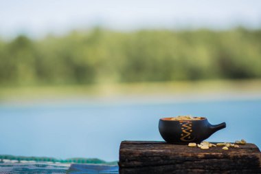 Çıtır, kızarmış ve tuzlu fıstık, soyulmuş. Doğal kahverengi ağaca doğal desenli bir arka plan üzerinde bir küçük kerimic tencerede besleyici snack. Temiz havada iştah açıcı yemek.