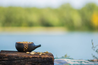 Çıtır, kızarmış ve tuzlu fıstık, soyulmuş. Doğal kahverengi ağaca doğal desenli bir arka plan üzerinde bir küçük kerimic tencerede besleyici snack. Temiz havada iştah açıcı yemek.