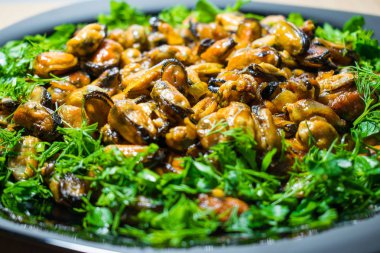 Kahve iştah açıcı midye yeşillik ile dekore edilmiş bir tabak üzerinde kızarmış.