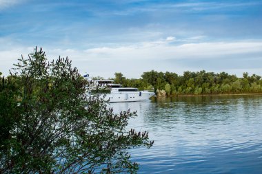 Bir gemi, bir mavna, bir yat, Rostov bölgesi Nehri üzerinde bir tekne. Su ulaştırma araçları yeşil yapraklı peyzaj ve mavi gökyüzü bulutlu arka planı suya yansıyan