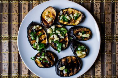 Taze sarımsak ve yeşillik bir tabakta yuvarlak beyaz, sıcak ve iştah açıcı ile mavi kızarmış patlıcan. Ev yapımı yemek. Lezzetli ızgara gıda