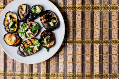 Taze sarımsak ve yeşillik bir tabakta yuvarlak beyaz, sıcak ve iştah açıcı ile mavi kızarmış patlıcan. Ev yapımı yemek. Lezzetli ızgara gıda