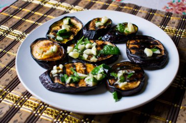 Taze sarımsak ve yeşillik bir tabakta yuvarlak beyaz, sıcak ve iştah açıcı ile mavi kızarmış patlıcan. Ev yapımı yemek. Lezzetli ızgara gıda