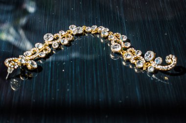 Kulağa altın, sarı küpe. Büyük ve küçük beyaz taşlarla akşam ve zarif süslemeleri. Altın takı ve Bijuteri