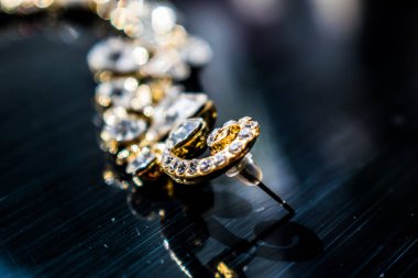 Kulağa altın, sarı küpe. Büyük ve küçük beyaz taşlarla akşam ve zarif süslemeleri. Altın takı ve Bijuteri