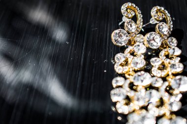 Kulağa altın, sarı küpe. Büyük ve küçük beyaz taşlarla akşam ve zarif süslemeleri. Altın takı ve Bijuteri