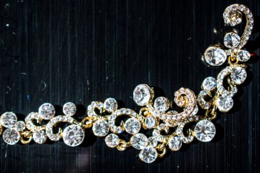 Kulağa altın, sarı küpe. Büyük ve küçük beyaz taşlarla akşam ve zarif süslemeleri. Altın takı ve Bijuteri