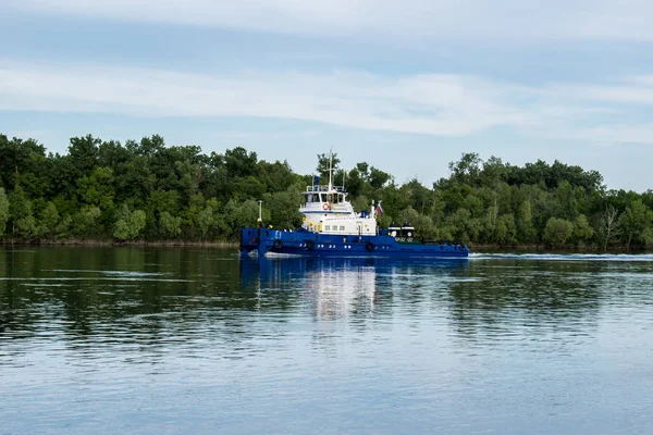 A ship, a barge, a yacht, a boat on the river in the Rostov region. Water transport against the background of a green leafy landscape and a blue sky with clouds reflected in the water
