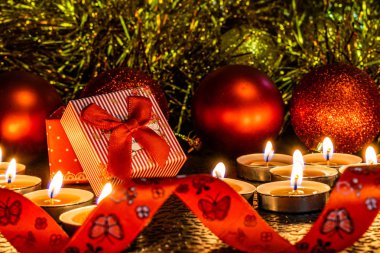 Noel ve yeni yıl kompozisyon Noel ağaçları ve metin için yer ile karanlık bir arka plan üzerinde mum ışığında altın tinsel kırmızı top. Tatil hediye, sürpriz. Kış koniler ve süsler güzel ışıklar.