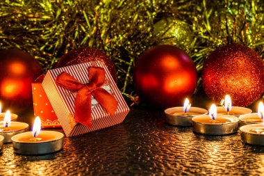 Noel ve yeni yıl kompozisyon Noel ağaçları ve metin için yer ile karanlık bir arka plan üzerinde mum ışığında altın tinsel kırmızı top. Tatil hediye, sürpriz. Kış koniler ve süsler güzel ışıklar.