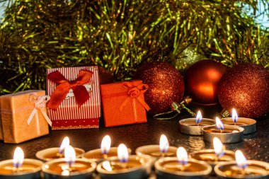 Noel ve yeni yıl kompozisyon Noel ağaçları ve metin için yer ile karanlık bir arka plan üzerinde mum ışığında altın tinsel kırmızı top. Tatil hediye, sürpriz. Kış koniler ve süsler güzel ışıklar.
