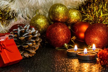 Noel ve yeni yıl kompozisyon Noel ağaçları ve metin için yer ile karanlık bir arka plan üzerinde mum ışığında altın tinsel kırmızı top. Tatil hediye, sürpriz. Kış koniler ve süsler güzel ışıklar.