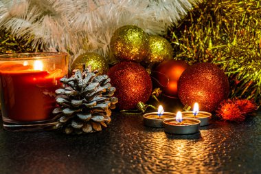 Noel ve yeni yıl kompozisyon Noel ağaçları ve metin için yer ile karanlık bir arka plan üzerinde mum ışığında altın tinsel kırmızı top. Tatil hediye, sürpriz. Kış koniler ve süsler güzel ışıklar.