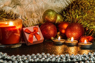 Noel ve yeni yıl kompozisyon Noel ağaçları ve metin için yer ile karanlık bir arka plan üzerinde mum ışığında altın tinsel kırmızı top. Tatil hediye, sürpriz. Kış koniler ve süsler güzel ışıklar.