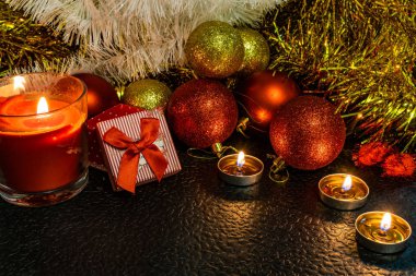 Noel ve yeni yıl kompozisyon Noel ağaçları ve metin için yer ile karanlık bir arka plan üzerinde mum ışığında altın tinsel kırmızı top. Tatil hediye, sürpriz. Kış koniler ve süsler güzel ışıklar.