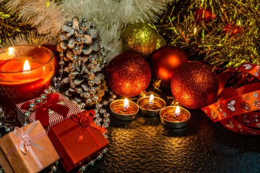 Noel ve yeni yıl kompozisyon Noel ağaçları ve metin için yer ile karanlık bir arka plan üzerinde mum ışığında altın tinsel kırmızı top. Tatil hediye, sürpriz. Kış koniler ve süsler güzel ışıklar.