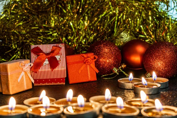 Noel ve yeni yıl kompozisyon Noel ağaçları ve metin için yer ile karanlık bir arka plan üzerinde mum ışığında altın tinsel kırmızı top. Tatil hediye, sürpriz. Kış koniler ve süsler güzel ışıklar.