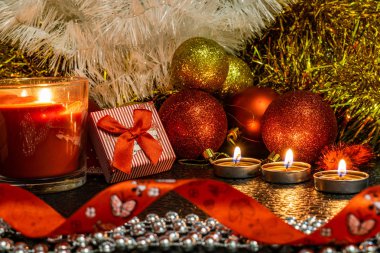 Noel ve yeni yıl kompozisyon Noel ağaçları ve metin için yer ile karanlık bir arka plan üzerinde mum ışığında altın tinsel kırmızı top. Tatil hediye, sürpriz. Kış koniler ve süsler güzel ışıklar.