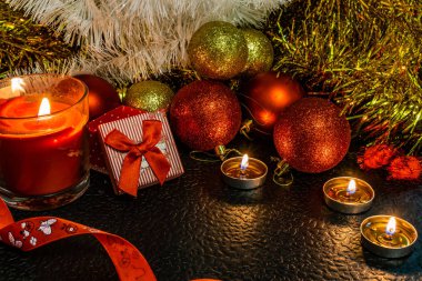 Noel ve yeni yıl kompozisyon Noel ağaçları ve metin için yer ile karanlık bir arka plan üzerinde mum ışığında altın tinsel kırmızı top. Tatil hediye, sürpriz. Kış koniler ve süsler güzel ışıklar.