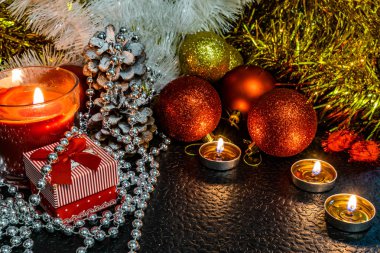 Noel ve yeni yıl kompozisyon Noel ağaçları ve metin için yer ile karanlık bir arka plan üzerinde mum ışığında altın tinsel kırmızı top. Tatil hediye, sürpriz. Kış koniler ve süsler güzel ışıklar.