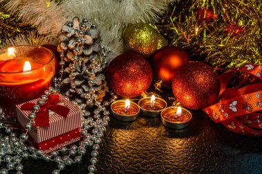 Noel ve yeni yıl kompozisyon Noel ağaçları ve metin için yer ile karanlık bir arka plan üzerinde mum ışığında altın tinsel kırmızı top. Tatil hediye, sürpriz. Kış koniler ve süsler güzel ışıklar.