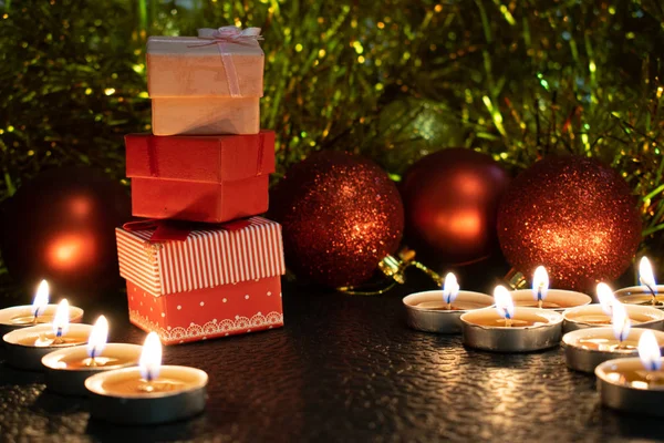 Noel ve yeni yıl kompozisyon Noel ağaçları ve metin için yer ile karanlık bir arka plan üzerinde mum ışığında altın tinsel kırmızı top. Tatil hediye, sürpriz. Kış koniler ve süsler güzel ışıklar.