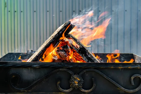 Metal ızgara, sahte, el yapımı, bir desen ile. Dumanlı Barbekü ve ızgara ürünleri için ahşap sıcak bir ateşe verdim. Güneşli bir günde dışarıda.