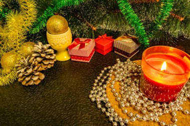 Mum, hediye kutuları ve Gümüş boncuk şenlikli Noel kompozisyonu. Süslemeleri yılbaşı gecesi için. Karanlık bir arka plan üzerinde sıcak ışık süslemeleri, koniler, stand ve ışıklar yeşil çam yazıtlar için boşluk ve boş alan arasında 