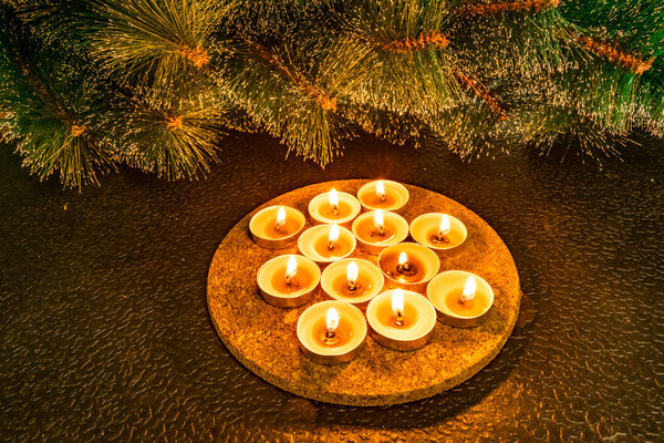 Новый год и Рождество, зеленая искусственная сосна на черном фоне в свете восковых свечей. Желтые теплые домашние прикосновения, подсветка на цокольном этаже трубки. Зажигание небольших свечей чая на текстуре с пустым местом для текста и добавление
.