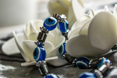 Kadınlar Günü için doğal taşlardan yapılmış mavi bilezik, 8 Mart. Nazar, öfke ve detractors gözleri ve göz bebeği şeklinde Şekil. Beyaz güller ile gri kadife üzerinde.