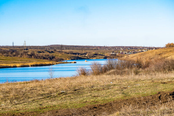 Ранняя весна пейзаж, в Ростовской области в городе Шахты, на реке Грушевка. Солнечный закат в желтом и оранжевом теплом свете. Сухая трава на местном берегу и красивое отражение в й
