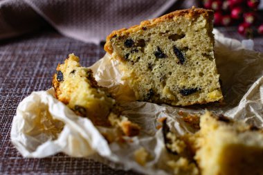 İçinde kuru erik olan büyük bir dilim ev yapımı turta. Portakal ve Elma, kağıt üzerinde kesilmiş. Lezzetli kek kırıntılarının yanında böğürtlen ve meyveli kek gibi gözenekli hamur işi.