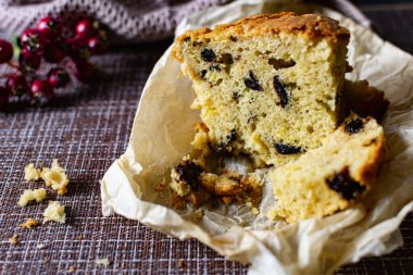 İçinde kuru erik olan büyük bir dilim ev yapımı turta. Portakal ve Elma, kağıt üzerinde kesilmiş. Lezzetli kek kırıntılarının yanında böğürtlen ve meyveli kek gibi gözenekli hamur işi.