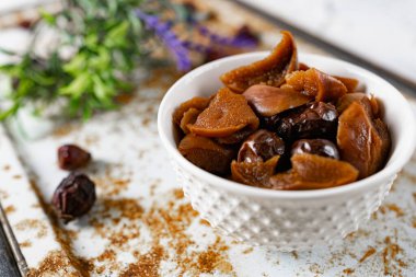 Tatlı ve yumuşak kurutulmuş elma ve tatlı için hazırlanmış gül kalçaları, alışılmadık beyaz ve paslı metal arka planda lavanta ve kuru meyvelerle süslenmiş.