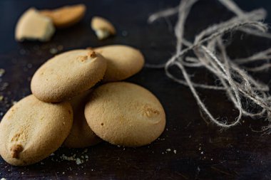 Ev yapımı bisküvi, yuvarlak şekilli hamur işi eski, karanlık bir yüzey üzerindeki kırıntılar yığını. Ve köyün çuval bezi iplikleri