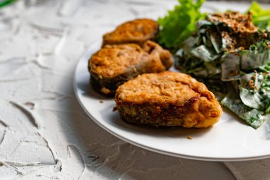 Kızarmış susam tohumu ile kaplanmış, kızartılmış kırmızı balık bifteğinin yanında ekmek kırıntıları içinde pembe somon balığı salatası ve ekşi krema salatası ile nefis bir yemek.